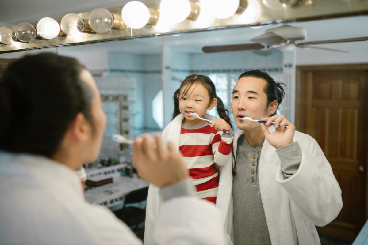man and child brushing their teeth