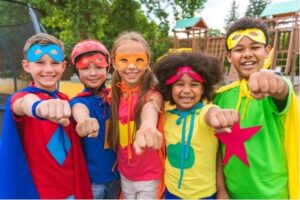 A group of elementary aged kids wearing colorful superhero costumes