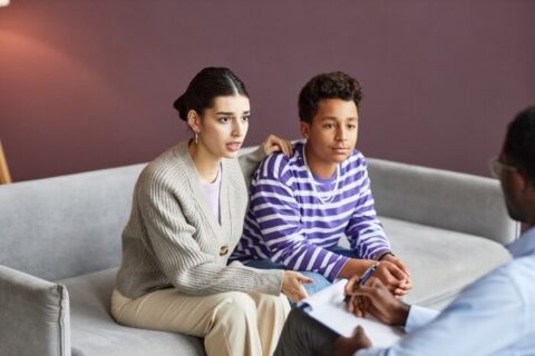 A man and a woman seated on a couch, engaged in a counseling session with a mental health professional