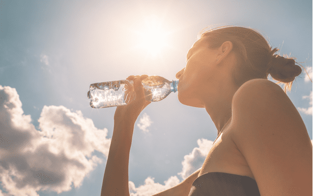 Woman hydrating herself by drinking water on a sunny day