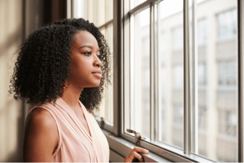 Woman looking out window from her home in Brevard County, Florida