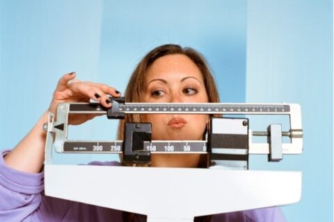 A woman weighs herself on a standing scale