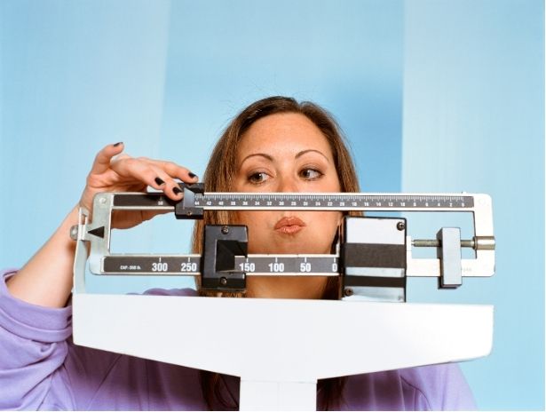 A woman weighs herself on a standing scale