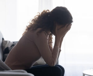 Stressed woman sitting, hands on face, dealing with mental trauma in Brevard County, FL