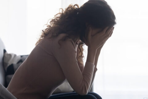 Stressed woman sitting, hands on face, dealing with mental trauma in Brevard County, FL